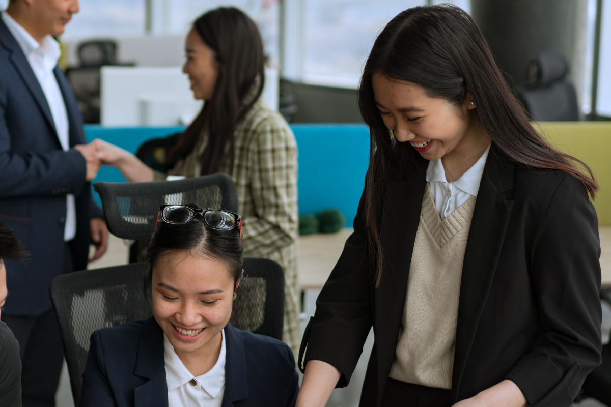 An image of a group of coworkers in the office chatting and smiling.
